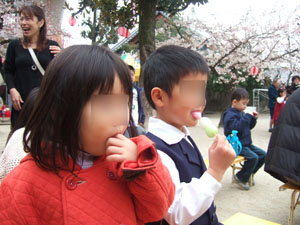 演奏や人形劇に見入りながら団子を食べる@幼稚園の桜祭り